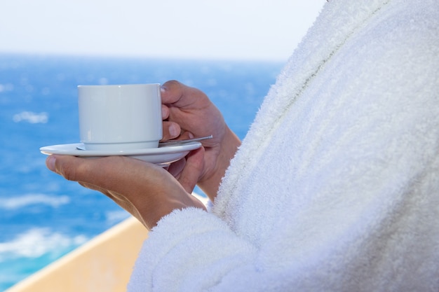 Tasse Kaffee in männlichen Händen über Meerblick