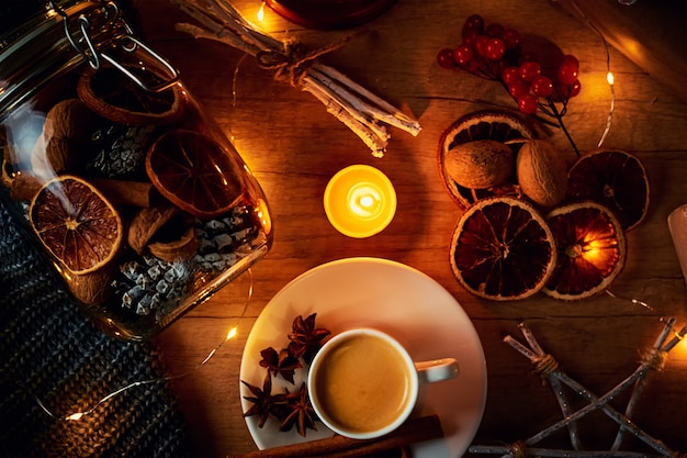 Tasse Kaffee, Kerzen und Dekorationen mit einer Girlande beleuchtet, Draufsicht