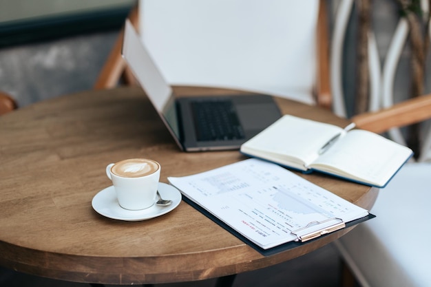 Tasse Kaffee-Klemmbrett und Laptop auf dem Tisch