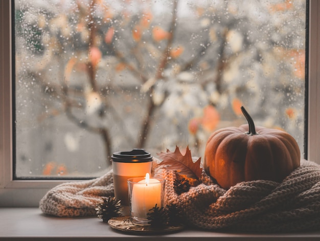 Tasse kaffee, kürbis, getrocknetes herbstlaub am fenster. herbstkomposition.