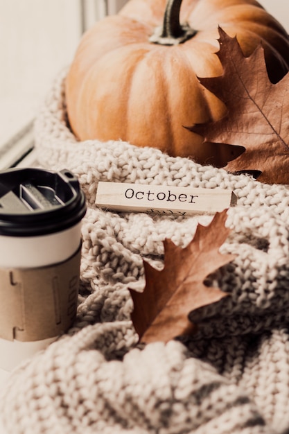 Tasse kaffee, kürbis, getrocknetes herbstlaub am fenster.