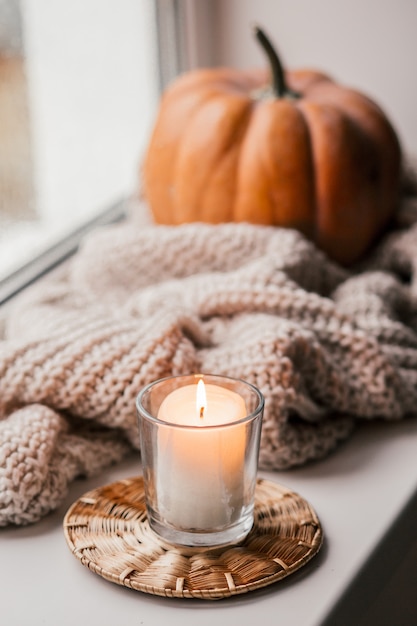 Tasse Kaffee, Kürbis, getrocknetes Herbstlaub am Fenster.