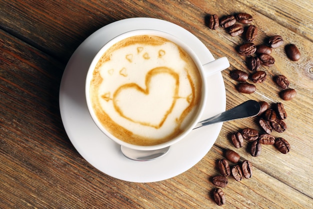 Tasse Kaffee Latte Art mit Körnern auf Holzhintergrund