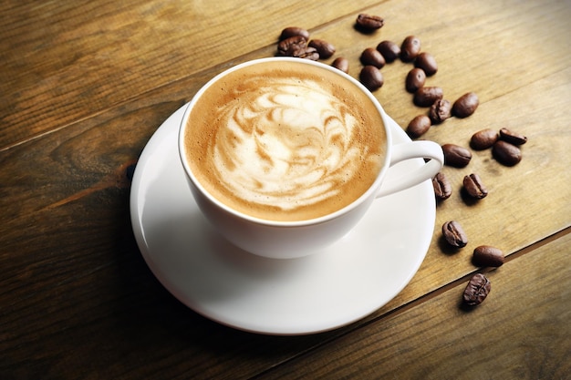 Tasse Kaffee Latte Art mit Körnern auf Holzhintergrund