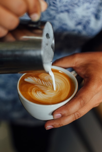 Tasse Kaffee Lattekunst auf dem hölzernen Schreibtischcafé-Café