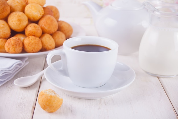 Tasse Kaffee mit Bällchen von frisch gebackenen selbst gemachten Hüttenkäsekrapfen in einer Platte auf einem Hintergrund.