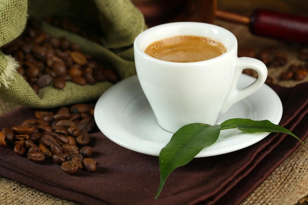 Tasse Kaffee mit Bohnen auf dem Tisch aus nächster Nähe