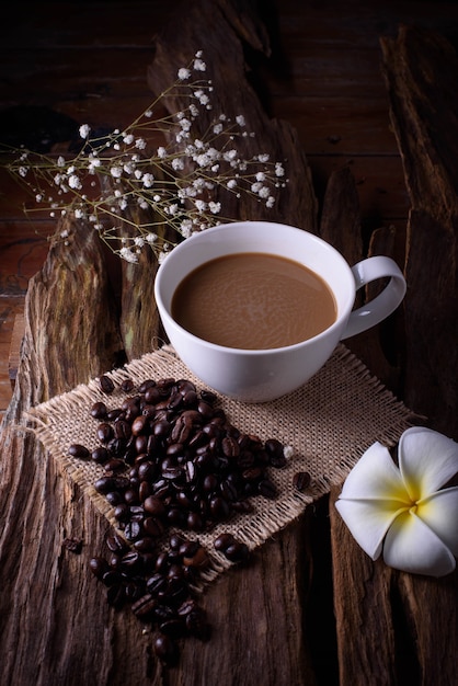 Tasse Kaffee mit Bohnen auf Holztisch.