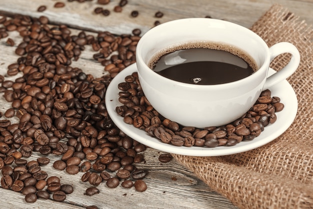 Tasse Kaffee mit Bohnen auf Tabelle