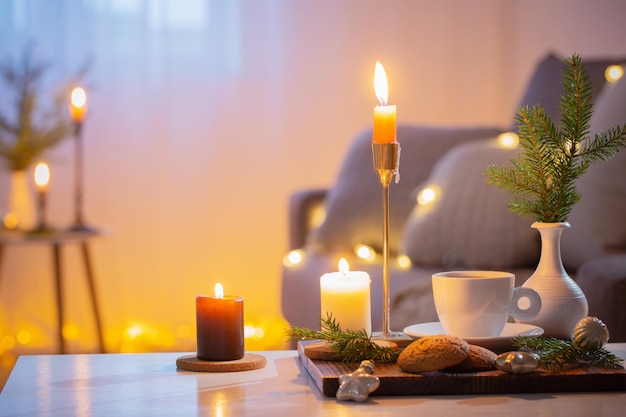 Tasse Kaffee mit brennenden Kerzen und Weihnachtsschmuck zu Hause