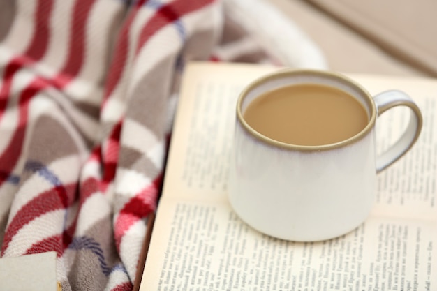 Tasse Kaffee mit Buch auf Sofa im Wohnzimmer