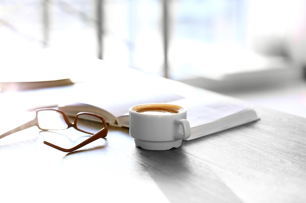 Tasse Kaffee mit Buch und Gläsern auf dem Tisch