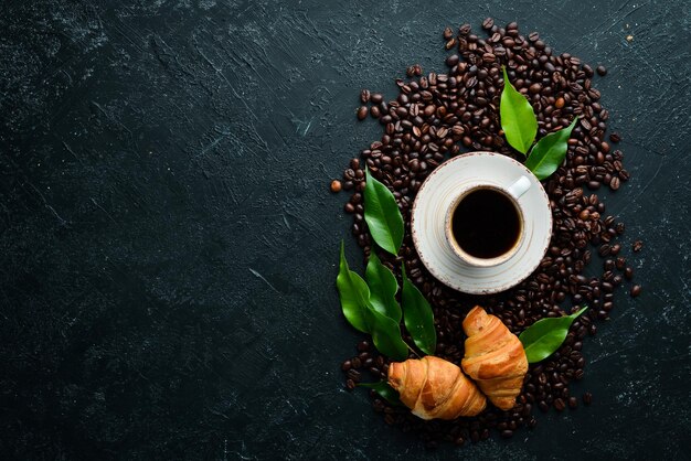 Tasse Kaffee mit Croissant Frühstück auf schwarzem Steinhintergrund Draufsicht Freier Platz für Ihren Text