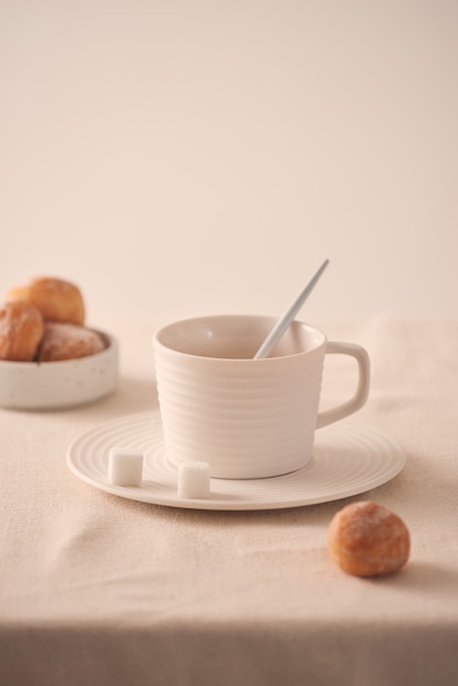 Tasse Kaffee mit Donuts zum Frühstück auf hellem Hintergrund