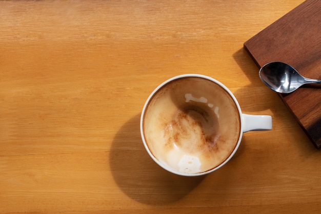 Tasse Kaffee mit Draufsicht wurde mit Löffel auf braunem Holztisch mit Kopienraum für Text getrunken