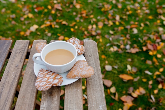 Tasse Kaffee mit Herzformplätzchen auf einem Tisch in der Herbstsaisonzeit