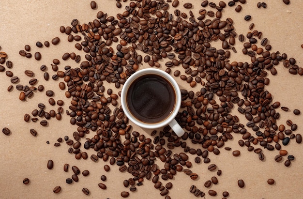 Tasse Kaffee mit Kaffeebohnen auf Draufsicht des Papierhintergrundes