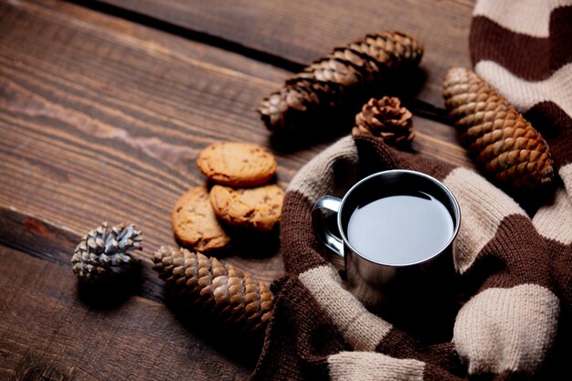 Tasse Kaffee mit Keksen und Schal auf Holztisch