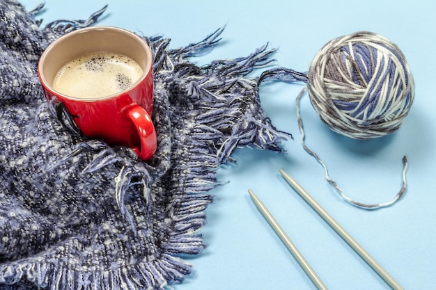 Tasse Kaffee mit Knäuel aus natürlichem Wollgarn und Stricknadeln