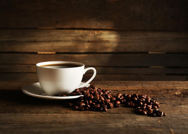 Tasse Kaffee mit Körnern auf hölzernem Hintergrund