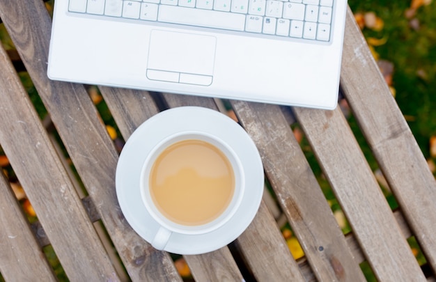 Tasse Kaffee mit Laptop-Computer auf Tabelle