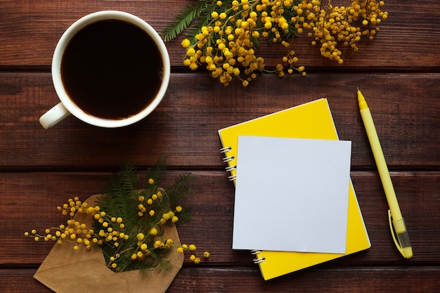 Tasse Kaffee mit leerem Papierrohling und Stift auf Holztisch