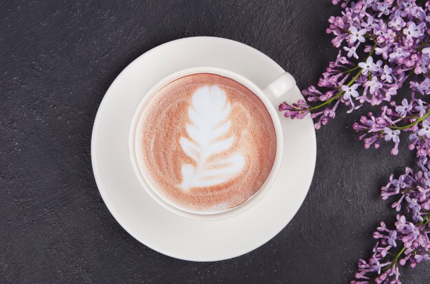 Tasse Kaffee mit lila Blumen