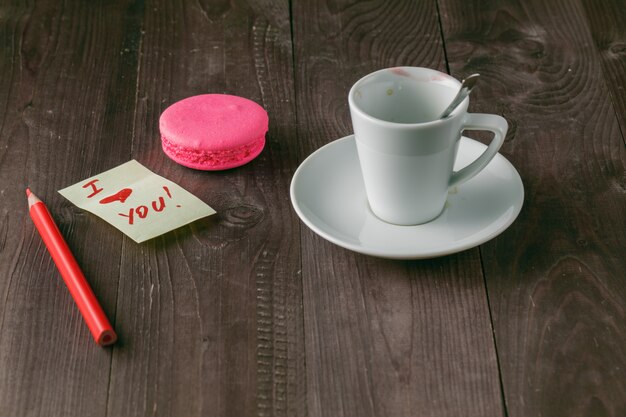 Tasse Kaffee mit Lippenstiftmarkierung und Notiz "Ich liebe dich" auf Tischnahaufnahme