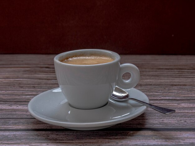 Tasse Kaffee mit Löffel auf rustikalem Hintergrund. Es hat oben negativen Raum.