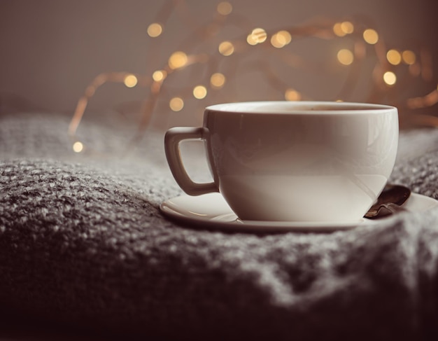 Tasse Kaffee mit Milch auf gemütlich gestrickter Winterdecke