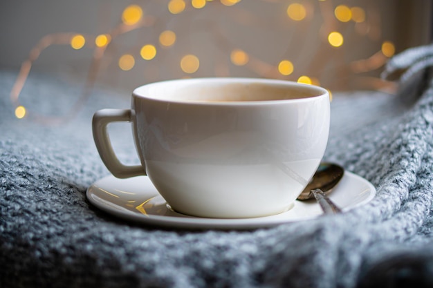 Tasse Kaffee mit Milch auf gemütlich gestrickter Winterdecke