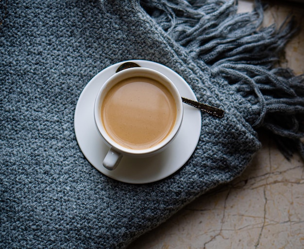 Tasse Kaffee mit Milch auf gemütlich gestrickter Winterdecke