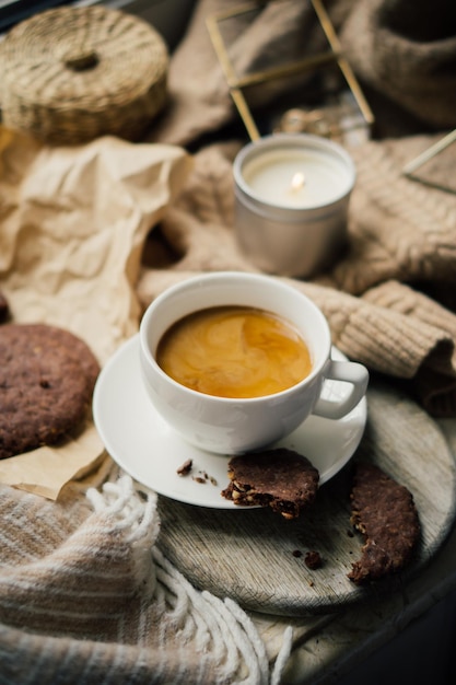 Tasse Kaffee mit Milch- und Schokoladenkeksen auf warmer Wolldecke