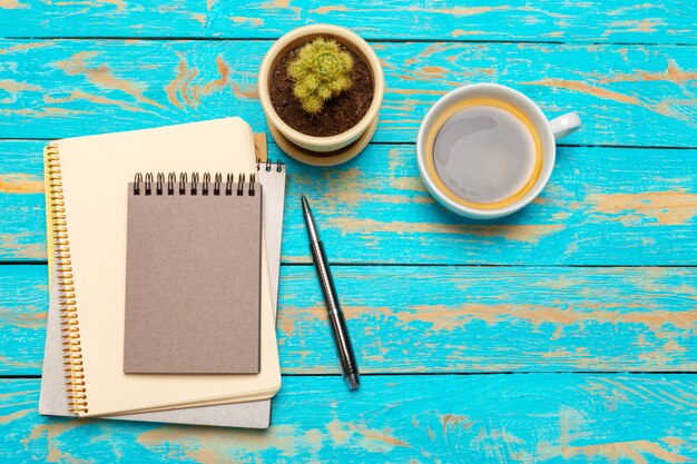 Tasse Kaffee mit Notizbuch auf hölzernem Schreibtisch