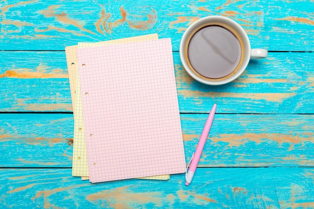 Tasse Kaffee mit Notizbuch auf hölzernem Schreibtisch