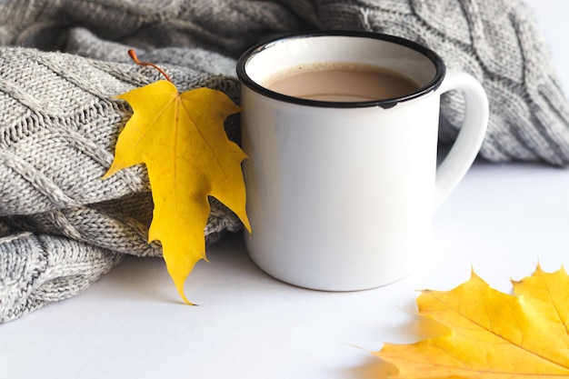 Tasse Kaffee mit Pullover und Herbstlaub