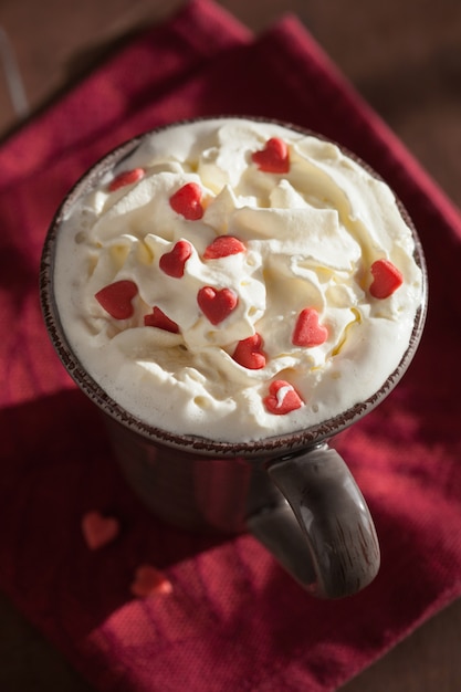 Tasse Kaffee mit Schlagsahne und roten Herzen