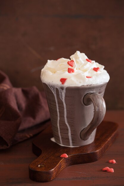 Tasse Kaffee mit Schlagsahne und roten Herzen