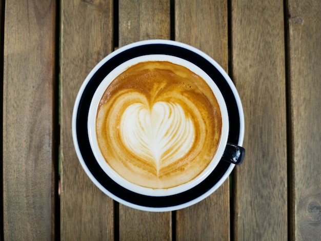 Tasse Kaffee mit schöner Lattekunst auf Holztisch