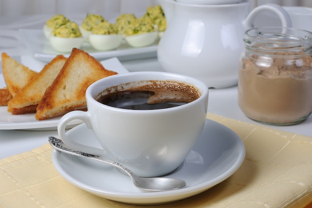 Tasse Kaffee mit Toast und einem Glas Paste, gefüllte Eier