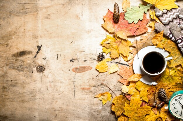 Tasse Kaffee mit Wecker auf Herbstlaub