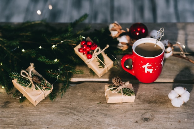 Tasse Kaffee mit Weihnachtsschmuck auf Holztisch.