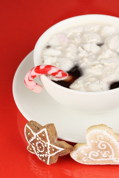 Tasse Kaffee mit Weihnachtssüße auf rotem Grund