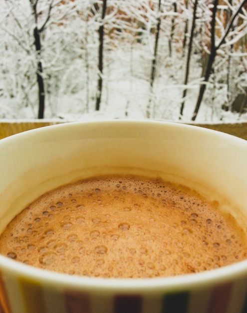 Tasse Kaffee mit Winterlandschaft im Hintergrund