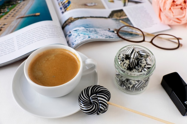 Tasse Kaffee mit wirbelnden schwarzen und weißen Lutscherbonbons in einem geöffneten Magazin aus Glas