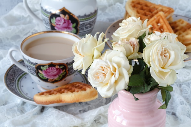 Tasse Kaffee mit zarten weißen Blumenrosen.