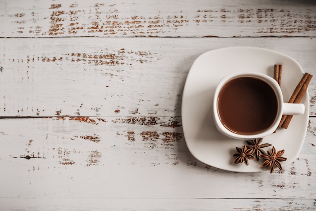 Tasse Kaffee mit Zimtstangen auf einem hellen hölzernen Hintergrund