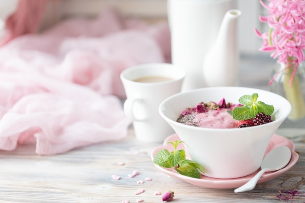 Tasse Kaffee, Müsli mit Erdbeeren, Nüssen und Milch.