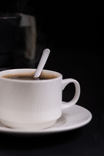 Foto tasse kaffee nahaufnahme mit löffel auf vorderansicht des schwarzen hintergrundes