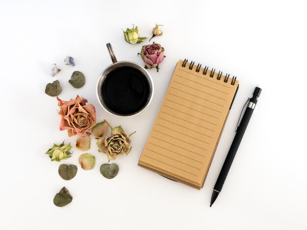 Tasse Kaffee, Skizzenbuch, Bleistift und getrocknete Blumen.